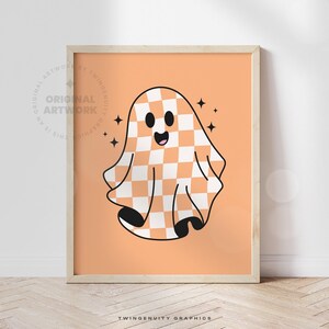 The orange ghost is printed on orange paper in a frame leaning against a wall with light streaming from the window.
