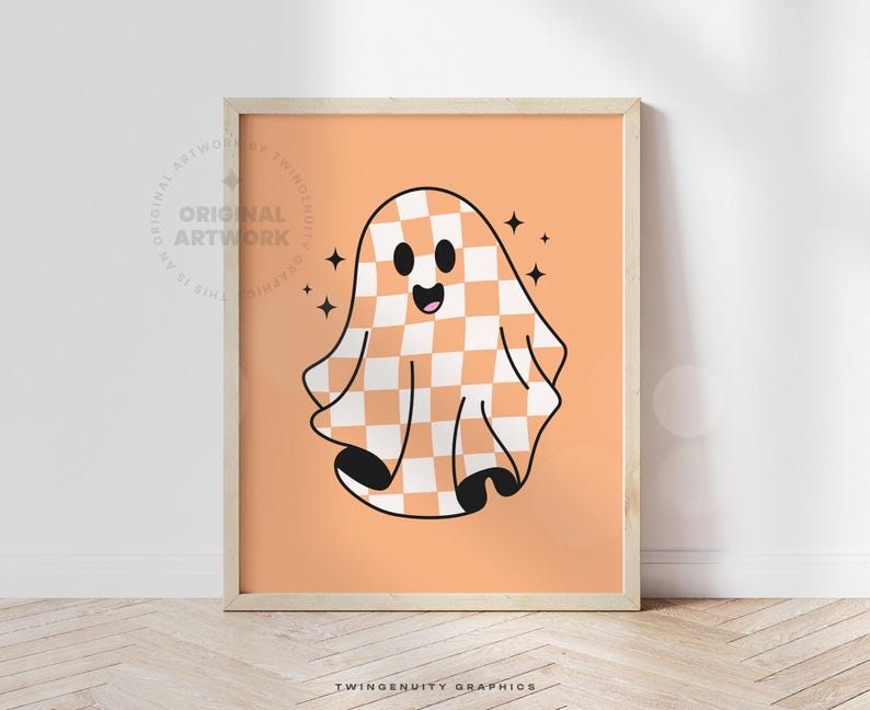 The orange ghost is printed on orange paper in a frame leaning against a wall with light streaming from the window.