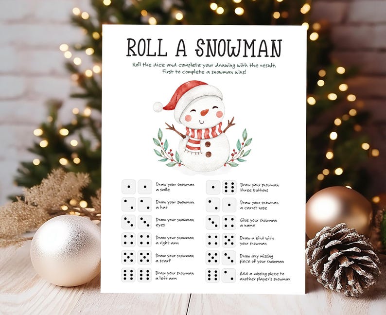 May include: A printable game card with instructions to "Roll a Snowman". The card features a watercolor illustration of a snowman with a red hat, black eyes, a carrot nose, and a striped scarf. The game involves rolling dice and completing a snowman drawing based on the dice roll.