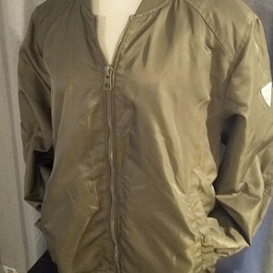 May include: A green bomber jacket with a zipper closure and a small logo on the right sleeve.