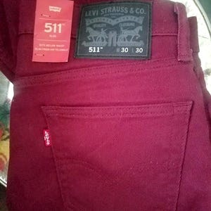 May include: Burgundy Levi's 511 Slim fit jeans. The jeans have a classic five-pocket design with a small red Levi's tag on the back pocket. The Levi Strauss & Co. label is visible on the back waistband. Waist size is W30 and length is 30 inches.