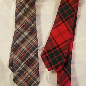 May include: Two neckties, one with a red, black, and green plaid pattern and the other with a blue, red, and white plaid pattern.
