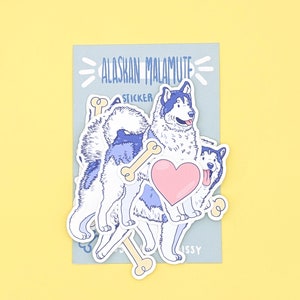 Puede incluir: Una hoja de pegatinas con un perro esquimal de Alaska de dibujos animados con un coraz&oacute;n y huesos. La hoja de pegatinas est&aacute; sobre un fondo azul con el texto "Alaskan Malamute Sticker".