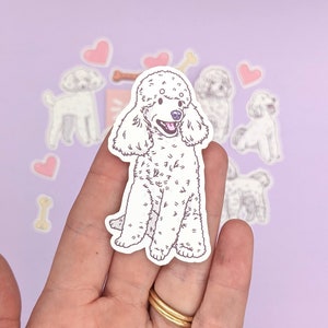 Op de afbeelding: Een witte poedel sticker met een roze hart en bot stickers op een paarse achtergrond.