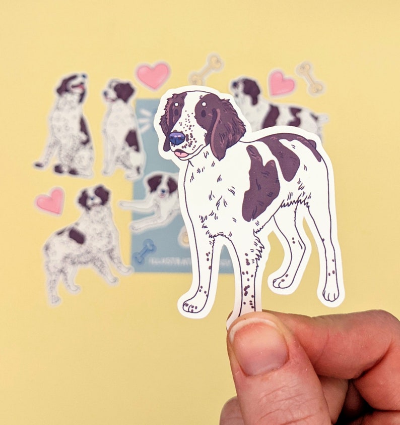 May include: A sticker of a brown and white dog with black spots. The dog is standing on all four legs and has its tongue sticking out. The sticker is on a yellow background.