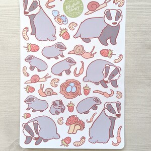 K&ouml;nnte beinhalten: Eine Bogen mit Aufklebern mit Illustrationen von Dachsen, Schnecken, Erdbeeren, Pilzen, Eiern und W&uuml;rmern. Die Aufkleber sind auf wei&szlig;em Hintergrund und haben ein hellrosa und graues Farbschema. Der Text "Illustrate Chrissy" befindet sich in der oberen rechten Ecke des Bogens.