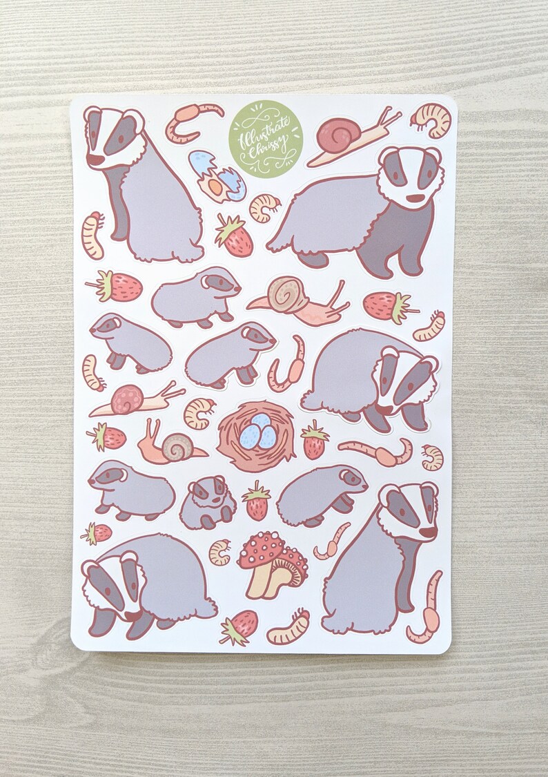 K&ouml;nnte beinhalten: Eine Bogen mit Aufklebern mit Illustrationen von Dachsen, Schnecken, Erdbeeren, Pilzen, Eiern und W&uuml;rmern. Die Aufkleber sind auf wei&szlig;em Hintergrund und haben ein hellrosa und graues Farbschema. Der Text "Illustrate Chrissy" befindet sich in der oberen rechten Ecke des Bogens.