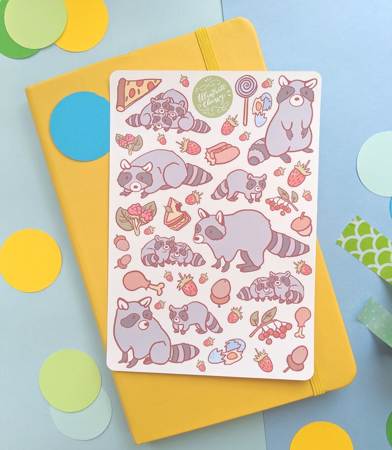 May include: A sticker sheet featuring cartoon raccoons, strawberries, pizza, and other food items. The raccoons are gray with striped tails. The text "Illustrate Chassy" is in a green circle. The sticker sheet is on a yellow notebook.