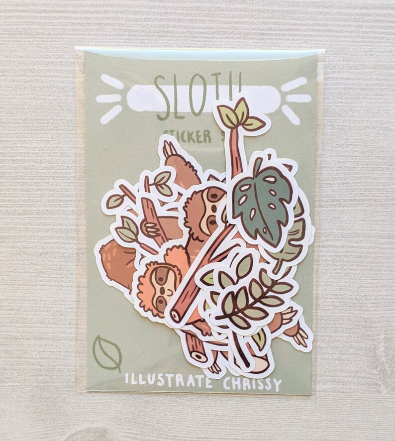 May include: A set of sloth stickers in a clear plastic bag. The stickers feature sloths hanging from branches, leaves, and the text "Sloth Sticker" and "Illustrate Chrissy".