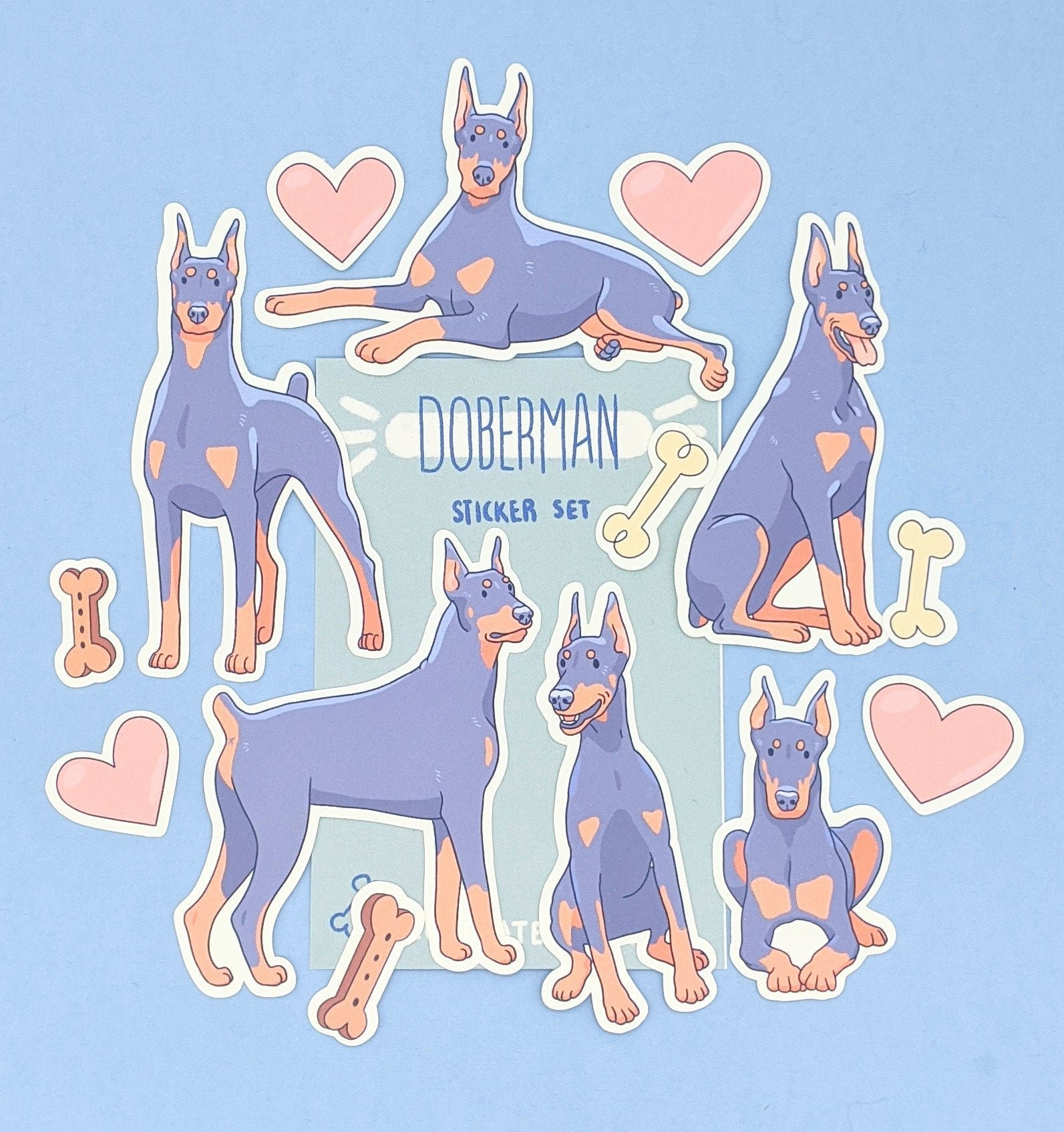 May include: A set of 9 Doberman Pinscher dog stickers in various poses. The stickers are in a cartoon style with pastel colors and feature a pink, blue, and white color scheme. The stickers are labeled "Doberman Sticker Set".
