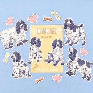 May include: A sticker set featuring Cocker Spaniel illustrations in black and white, with accents of pink hearts and bone shapes. The set includes stickers with the text "COCKER SPANIEL STICKER SET" and "ILLUSTRATE CHRISSY".