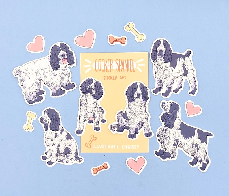 May include: A sticker set featuring Cocker Spaniel illustrations in black and white, with accents of pink hearts and bone shapes. The set includes stickers with the text "COCKER SPANIEL STICKER SET" and "ILLUSTRATE CHRISSY".