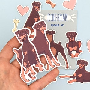 May include: A set of Doberman Pinscher dog stickers. The stickers are in various poses and feature brown and black fur. The stickers are on a light blue background. The text "Doberman Sticker Set" is on a gray background.