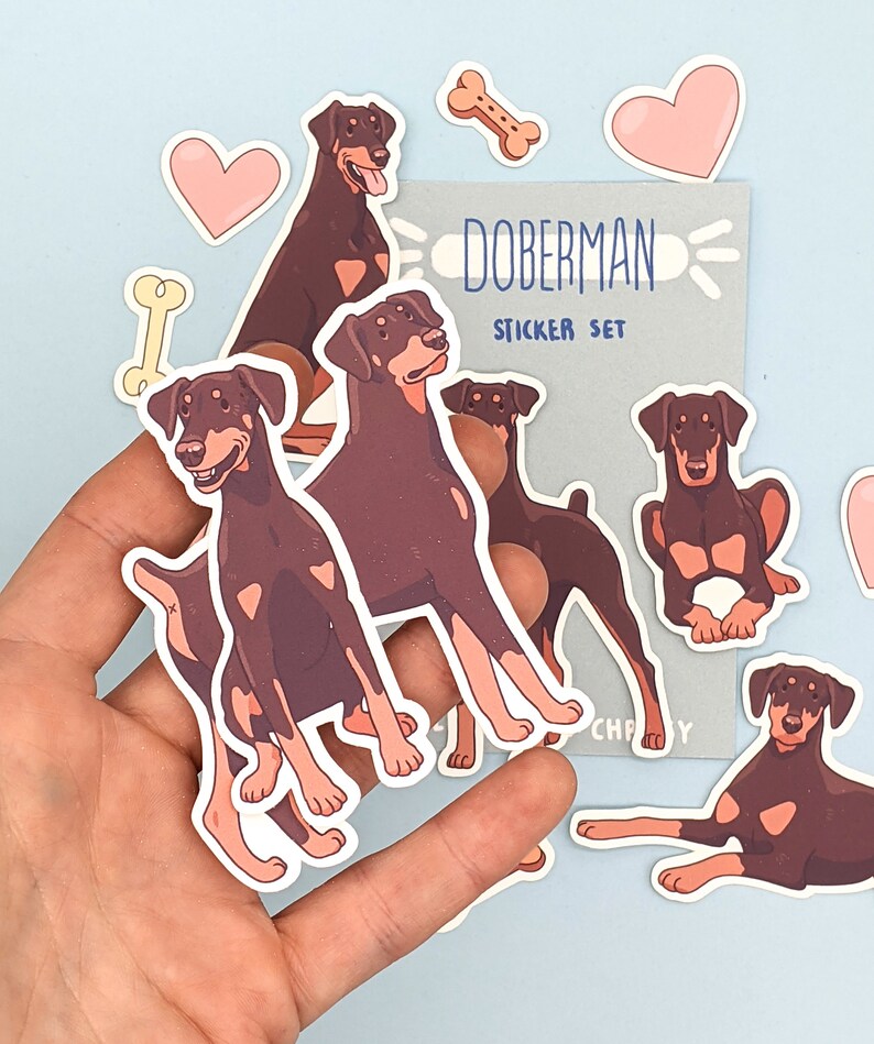 May include: A set of Doberman Pinscher dog stickers. The stickers are in various poses and feature brown and black fur. The stickers are on a light blue background. The text "Doberman Sticker Set" is on a gray background.