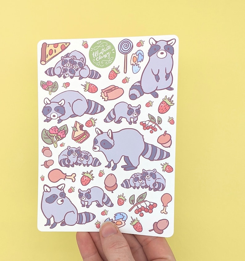 May include: A sticker sheet featuring cartoon raccoons and various food items like pizza, strawberries, and a lollipop. The sheet includes the text "Illustrate Chrissy" in a green circular design. The raccoons are in various poses, with gray and white fur.