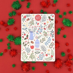 May include: A white sticker with a festive Christmas design featuring a blue pitcher, a blue vase, red berries, green leaves, and the text "Allegraite Christmas".
