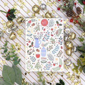 May include: A white card with a floral pattern and a red circle with the text "Celebrate Every Day" in white. The card is surrounded by gold and silver bells and red berries.
