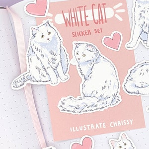 May include: A sticker set featuring illustrations of white cats with yellow eyes and pink heart stickers. The set includes a pink card with the text "WHITE CAT STICKER SET" and "ILLUSTRATE CHISSY". The stickers are placed on a dotted background.