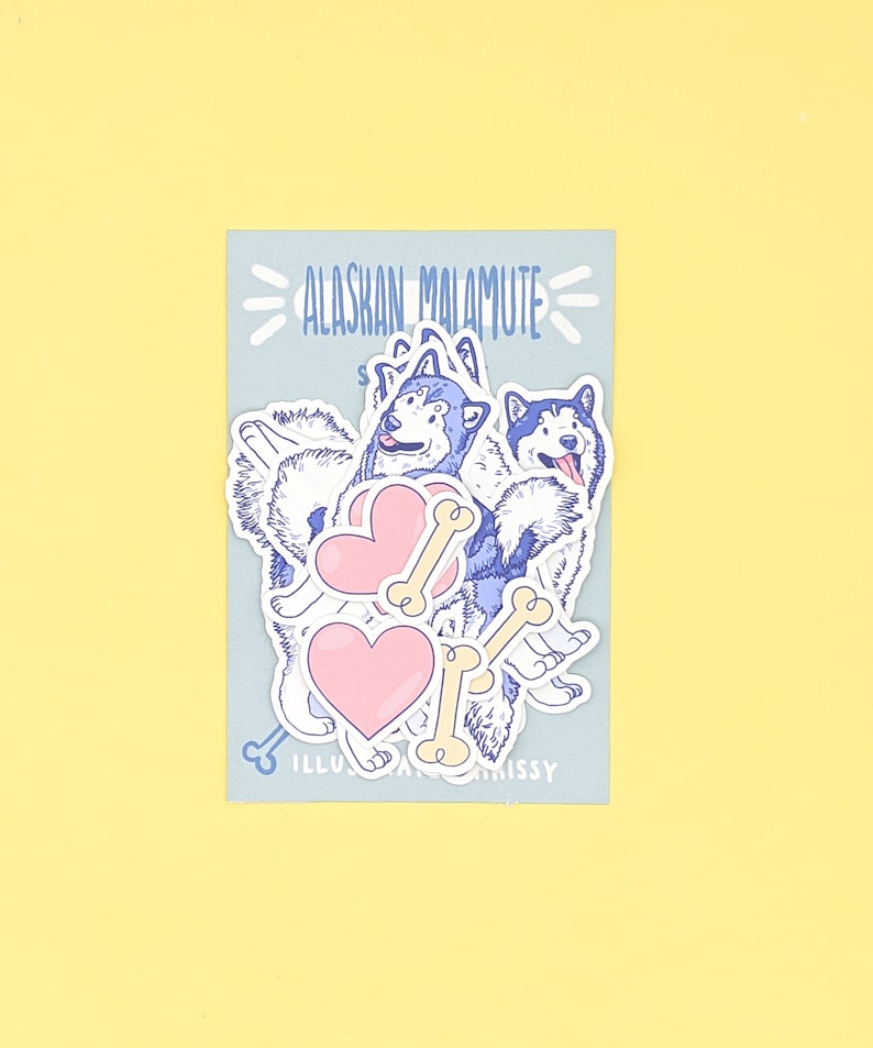 Puede incluir: Un conjunto de pegatinas con perros Alaskan Malamute con corazones y huesos. Las pegatinas est&aacute;n sobre un fondo azul claro con el texto "Alaskan Malamute" en azul.