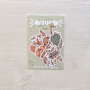 May include: A set of sloth stickers featuring multiple sloths hanging from branches with green leaves. The stickers are on a light green background with the text "Sloth Sticker" and "Illustrate Chrissy".