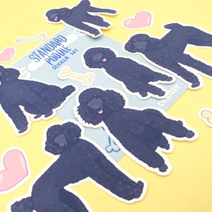 Op de afbeelding: Een stickerset met zwarte standaard poedels in verschillende poses. De stickers zijn op een gele achtergrond met roze harten en botvormige stickers. De tekst "STANDARD POODLE STICKER SET" staat op een blauwe achtergrond.