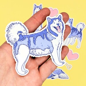 Puede incluir: Una pegatina azul y blanca de un perro Alaskan Malamute con una pegatina de coraz&oacute;n rosa y hueso en el fondo.