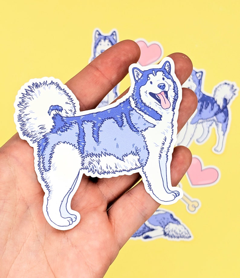 Puede incluir: Una pegatina azul y blanca de un perro Alaskan Malamute con una pegatina de coraz&oacute;n rosa y hueso en el fondo.