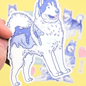 Puede incluir: Una pegatina azul y blanca de un perro esquimal de Alaska de dibujos animados con una cola esponjosa y la lengua fuera. La pegatina est&aacute; sobre un fondo amarillo.