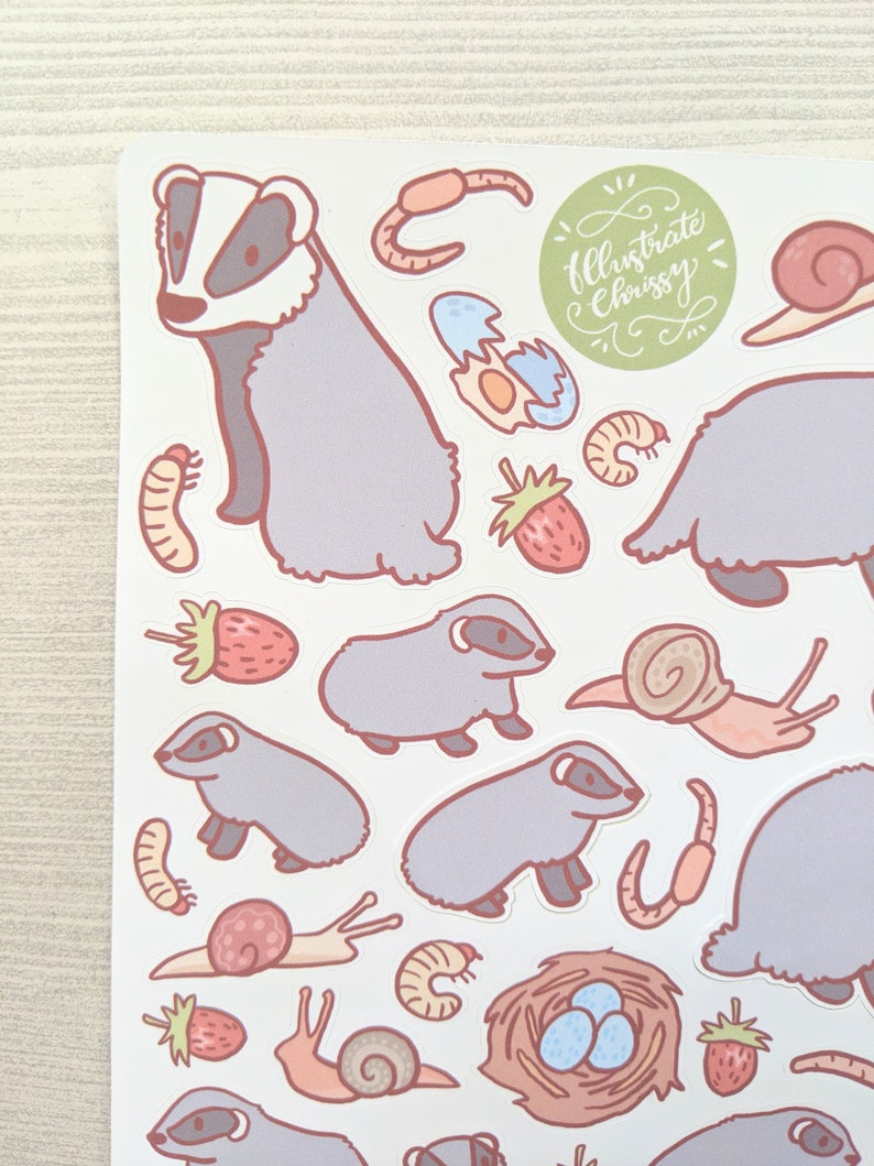 K&ouml;nnte beinhalten: Eine Bogen mit Aufklebern mit Illustrationen von Dachsen, Schnecken, Erdbeeren, W&uuml;rmern und Eiern. Die Aufkleber sind im Cartoon-Stil mit Pastellfarben gehalten. Der Text "Illustrate Chrissy" ist in Kursivschrift auf einem gr&uuml;nen Kreis geschrieben.