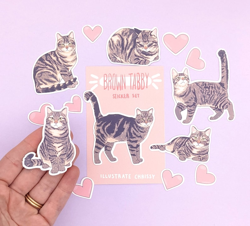 May include: A sticker set featuring nine brown tabby cats in various poses. The stickers are on a pink background with the text "Brown Tabby Sticker Set" and "Illustrate Chrissy".