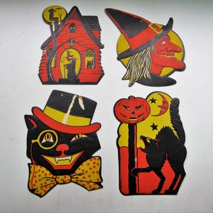 May include: Four vintage Halloween decorations. Includes a red house with a witch, a witch's face, a black cat with a monocle and top hat, and a pumpkin with a howling wolf. Each decoration has a yellow and black color scheme.