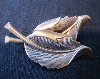 Puede incluir: Broche de hojas plateadas con dos hojas detalladas con vetas texturizadas. El broche tiene un diseño clásico, perfecto para añadir un toque de elegancia inspirada en la naturaleza a cualquier atuendo. Las hojas miden aproximadamente 5 cm.