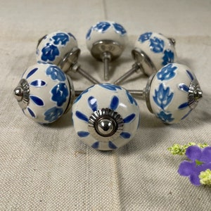 May include: Set of six white ceramic cabinet knobs with blue floral designs and silver metal accents.