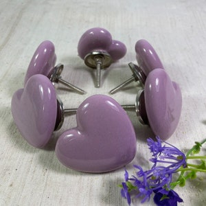 May include: Six purple heart-shaped ceramic drawer knobs with silver metal hardware.