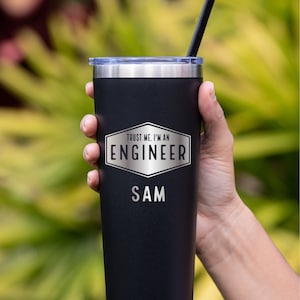 May include: Black stainless steel tumbler with a silver inscription that reads "Trust me, I'm an Engineer" and "Sam".