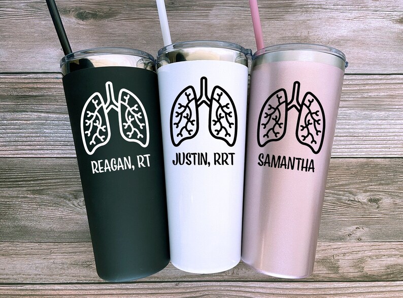 Puede incluir: Tres vasos de acero inoxidable con tapas negras y pajitas. Cada vaso presenta un contorno negro de pulmones y un nombre con un t&iacute;tulo de trabajo. Los vasos son negros, blancos y rosas.