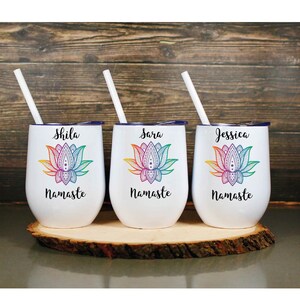 May include: Three white stainless steel tumblers with blue lids and rainbow mandala lotus flower designs. Each tumbler has a name, "Shila", "Sara", and "Jessica", and the word "Namaste" printed below the design.