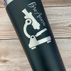 May include: Black stainless steel tumbler with a white microscope graphic and the name "BreAnna" engraved on the side.