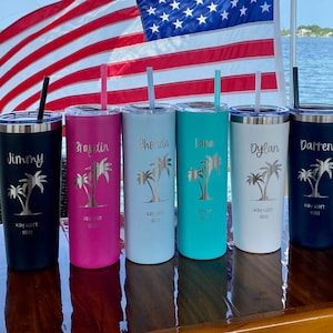May include: Five personalized stainless steel tumblers with palm tree designs and the words "Key West 2021" on each. The tumblers are in different colors: black, pink, light blue, turquoise, and dark blue. The names "Jimmy", "Braytin", "Phonda", "Lana", and "Darten" are engraved on the tumblers.