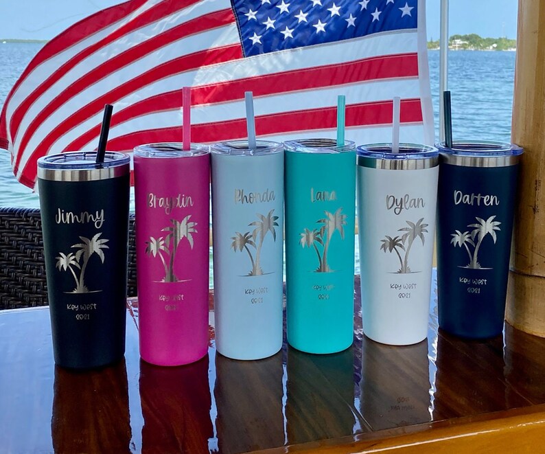May include: Five personalized stainless steel tumblers with palm tree designs and the words "Key West 2021" on each. The tumblers are in different colors: black, pink, light blue, turquoise, and dark blue. The names "Jimmy", "Braytin", "Phonda", "Lana", and "Darten" are engraved on the tumblers.