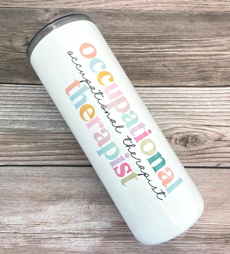 Pode incluir: Um copo de a&ccedil;o inoxid&aacute;vel branco com o texto "occupational therapist" em cores do arco-&iacute;ris.