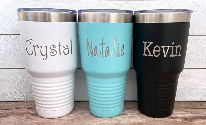 May include: Three stainless steel tumblers with personalized names: Crystal, Natalie, and Kevin. The tumblers are white, light blue, and black.