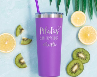 May include: Purple stainless steel tumbler with a straw. The tumbler has a silver lid and the text "Pilates is my happy hour Christa" is engraved on the front.