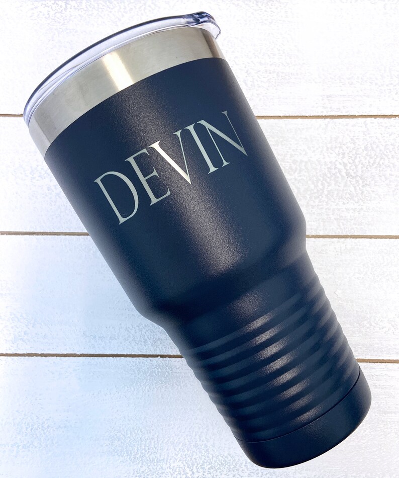 May include: A navy blue stainless steel tumbler with a white lid and the name "DEVIN" engraved on the side.