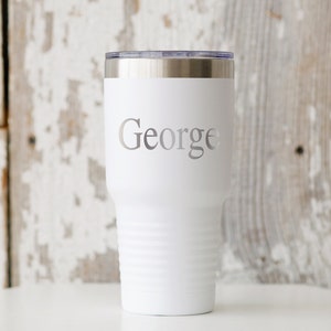 May include: White stainless steel tumbler with a silver lid and the name "George" engraved on the front.