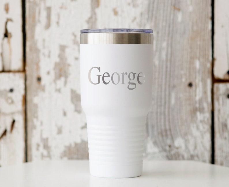 May include: White stainless steel tumbler with a silver lid and the name "George" engraved on the front.