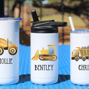 May include: Three white stainless steel tumblers with straw lids and personalized names. Each tumbler features a different yellow construction vehicle graphic: a cement mixer, a bulldozer, and a dump truck.