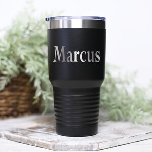 May include: Black stainless steel tumbler with a silver engraved name "Marcus".