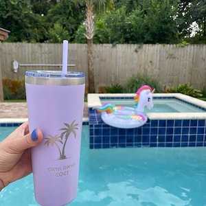 May include: A lavender stainless steel tumbler with a straw, featuring a palm tree design and the text "Destin, Florida 2021".