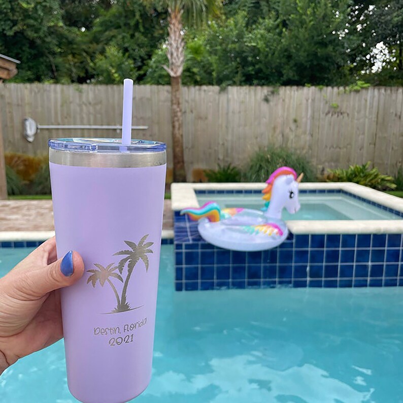 May include: A lavender stainless steel tumbler with a straw, featuring a palm tree design and the text "Destin, Florida 2021".